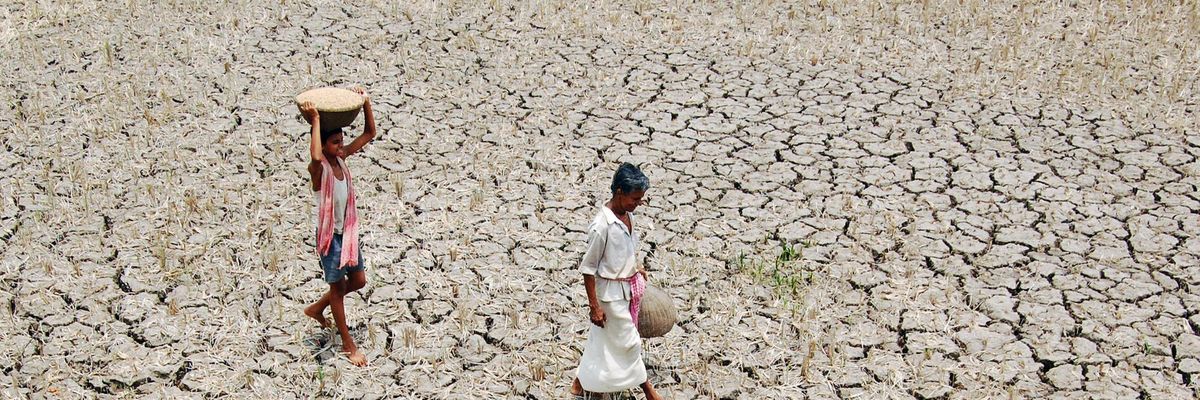 An Indian farmer and his son walk across a parched former field near Agartala, Tipura state