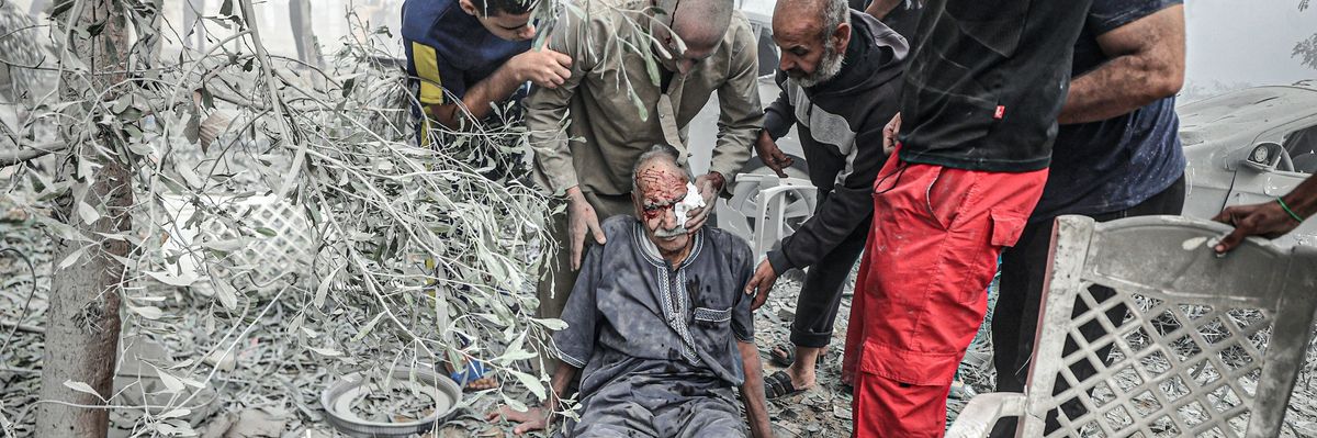 An injured elderly Palestinian man is helped after an Israeli airstrike