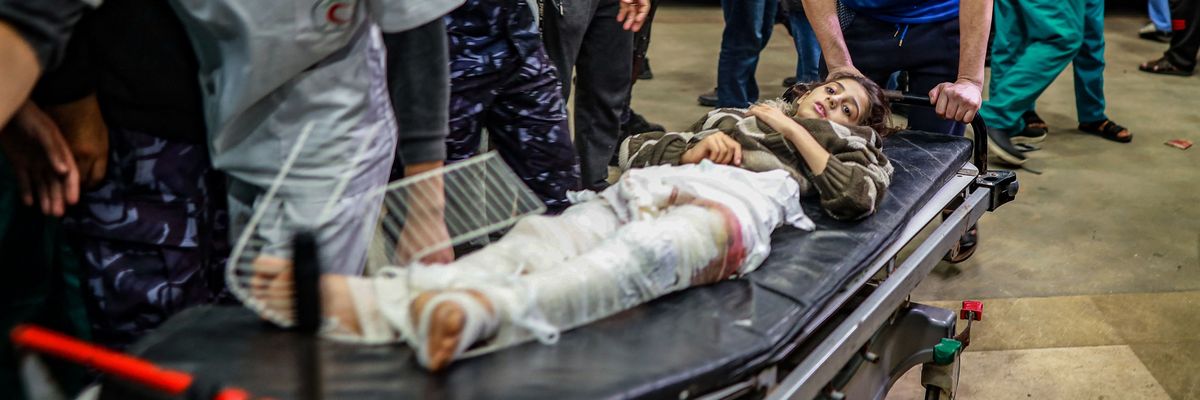 An injured Palestinian girl wrapped in bandages from the waist down is evacuated