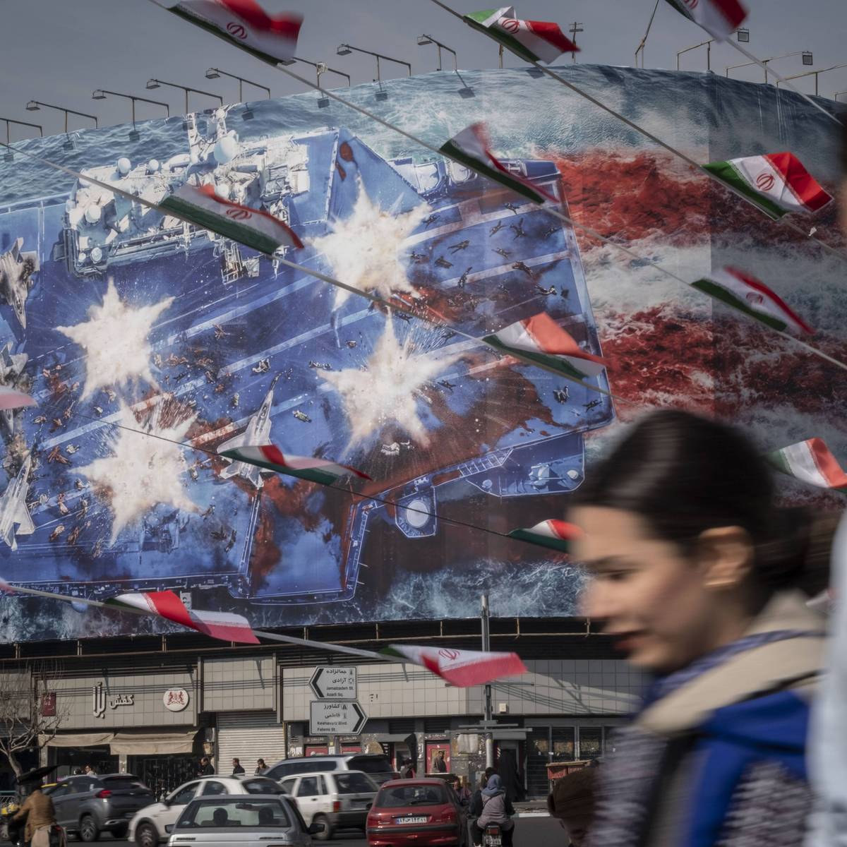 An Iranian man and women walk by an anti-American mural