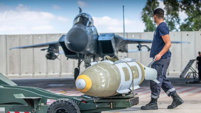 An Israel Defense Forces member loads a guided munition on a fighter jet