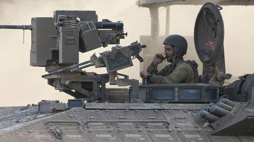 an Israeli army soldier sitting on an armored personnel carrier 