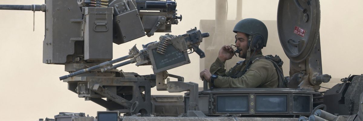 an Israeli army soldier sitting on an armored personnel carrier