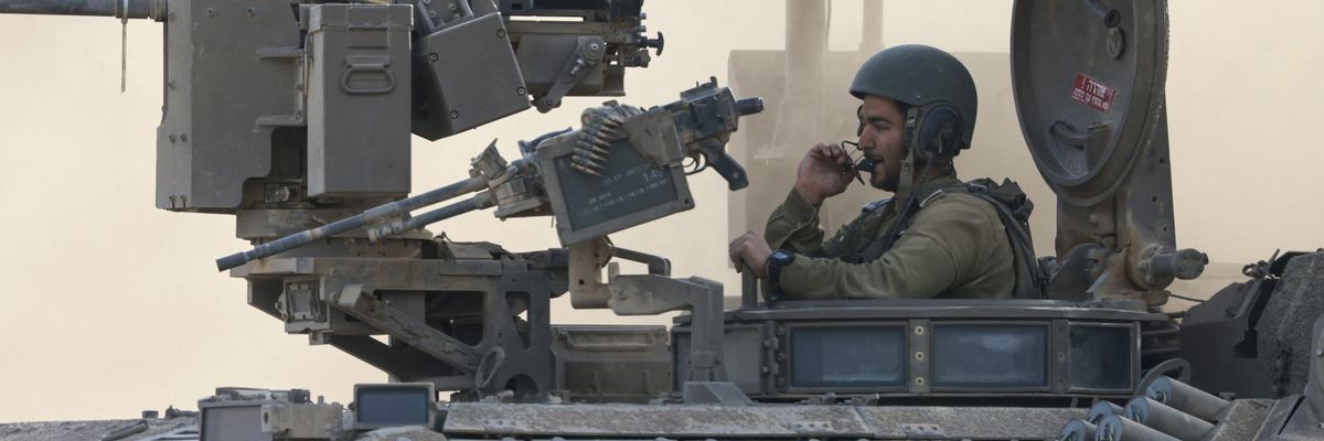 an Israeli army soldier sitting on an armored personnel carrier