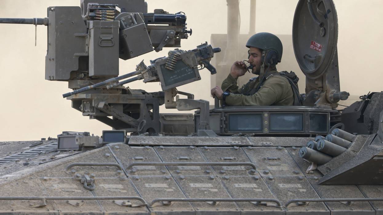 an Israeli army soldier sitting on an armored personnel carrier