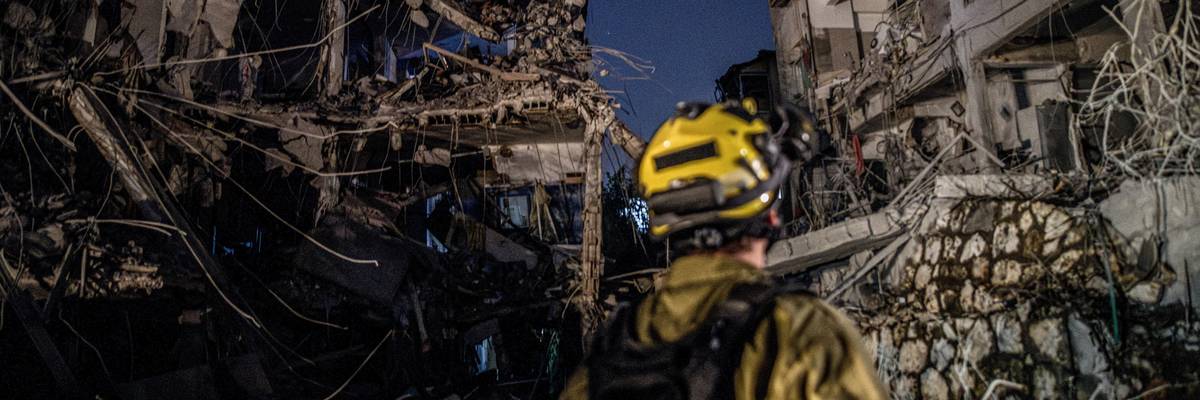 An Israeli Home Front Command soldier looks at a bombed building.