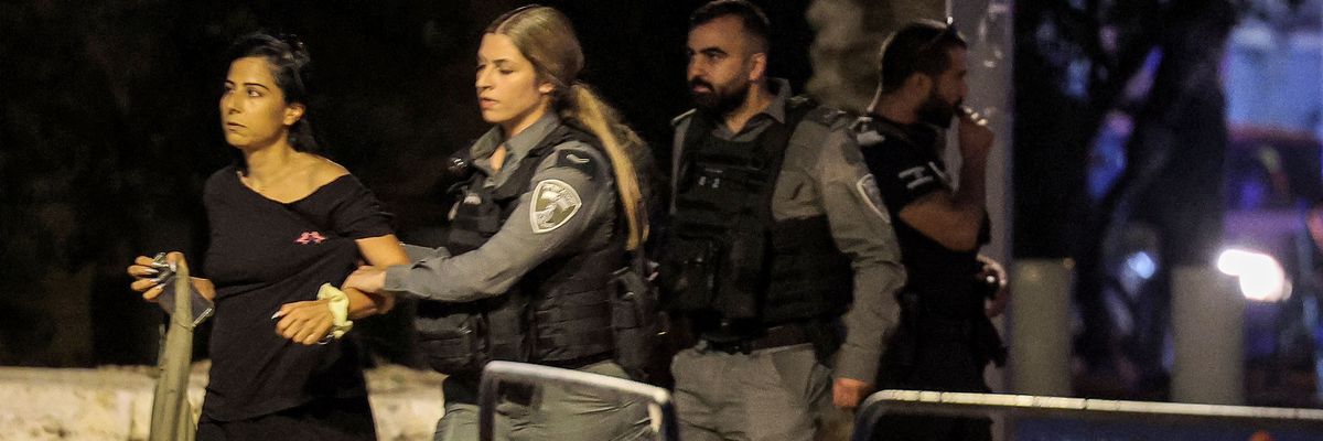 An Israeli policewoman detains a Palestinian citizen of Israel, who is wearing a black dress