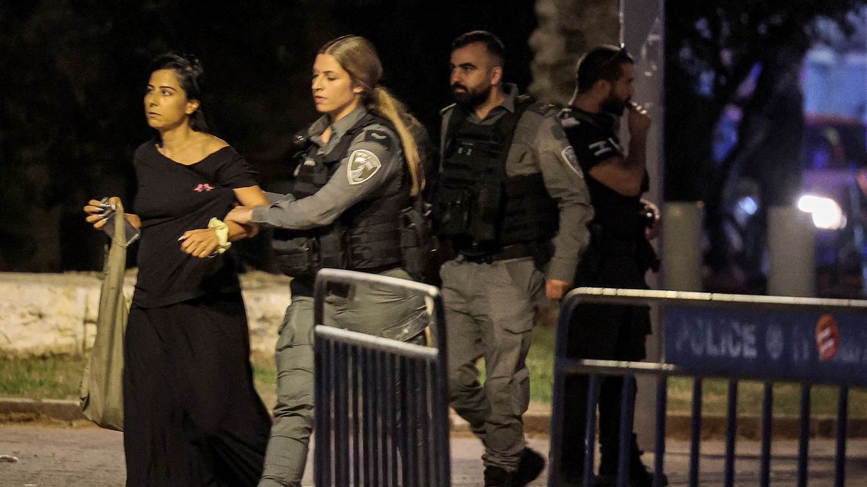 An Israeli policewoman detains a Palestinian citizen of Israel, who is wearing a black dress