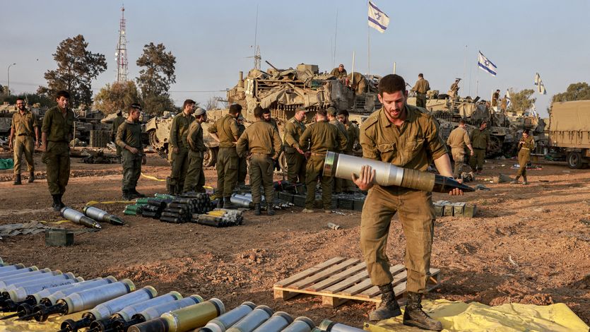 An Israeli soldier carries a heavy shell 