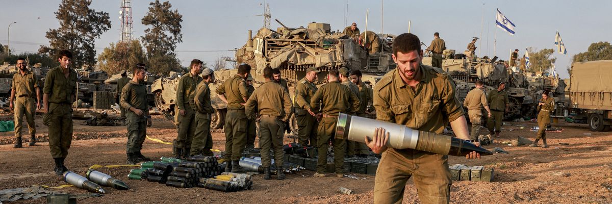 An Israeli soldier carries a heavy shell