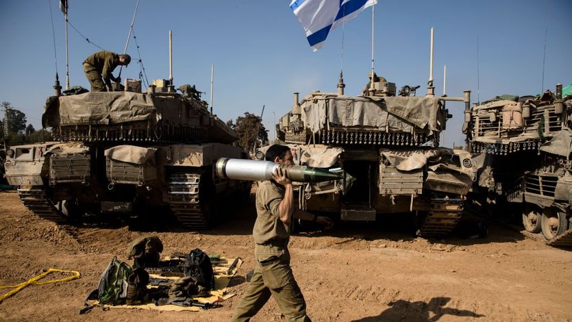 An Israeli soldier carries a tank shell 