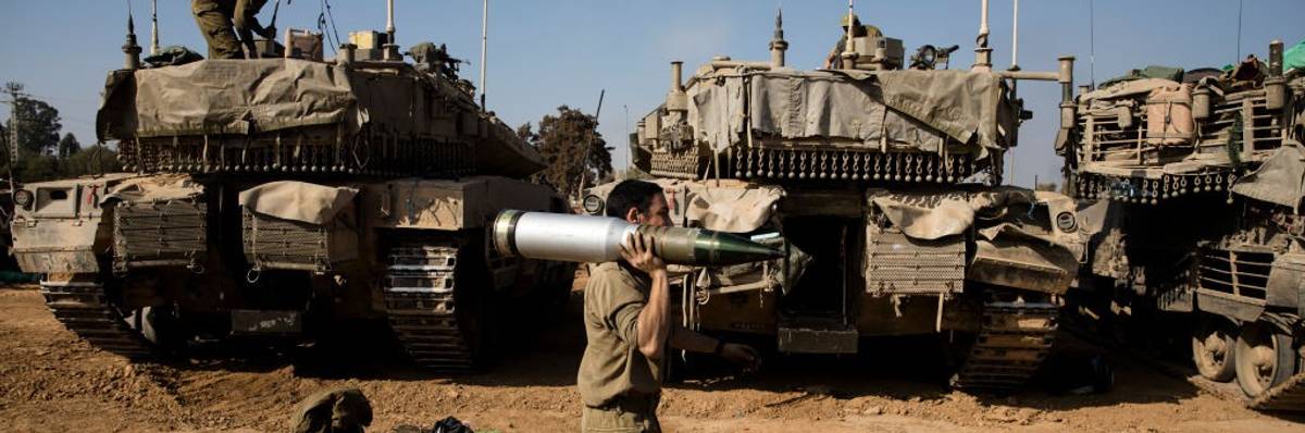 An Israeli soldier carries a tank shell