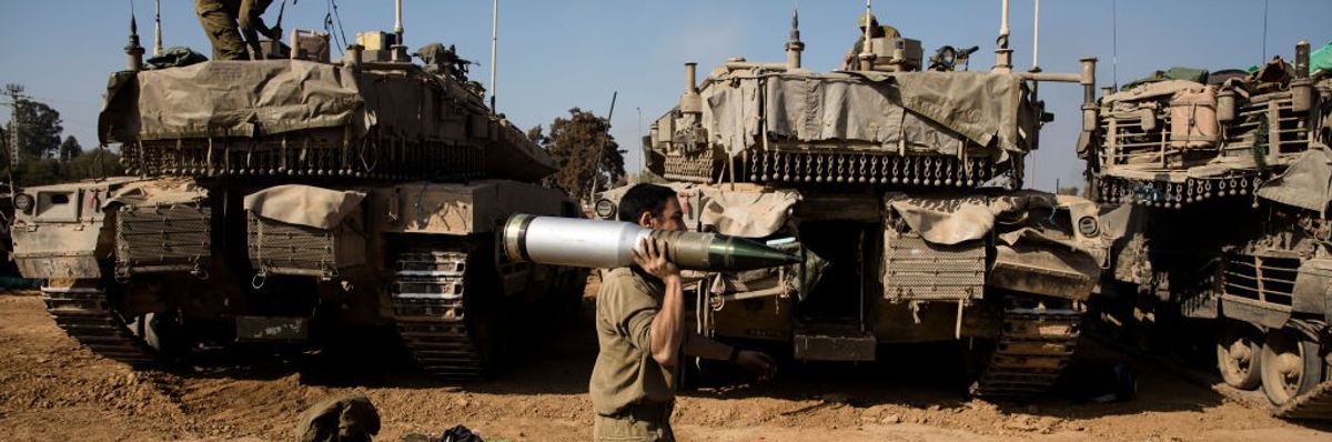 An Israeli soldier carries a tank shell 