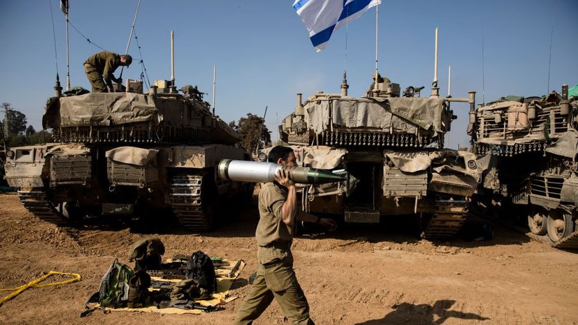 An Israeli soldier carries a tank shell