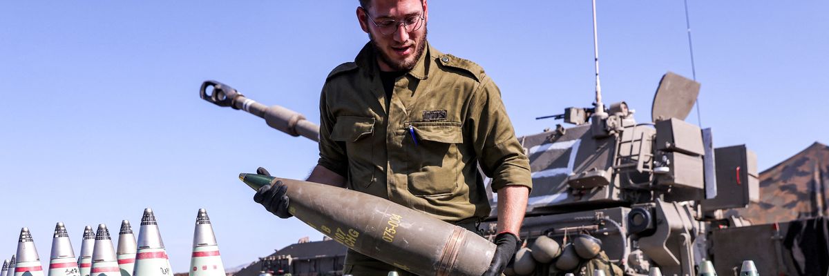 An Israeli soldier carries an artillery shell