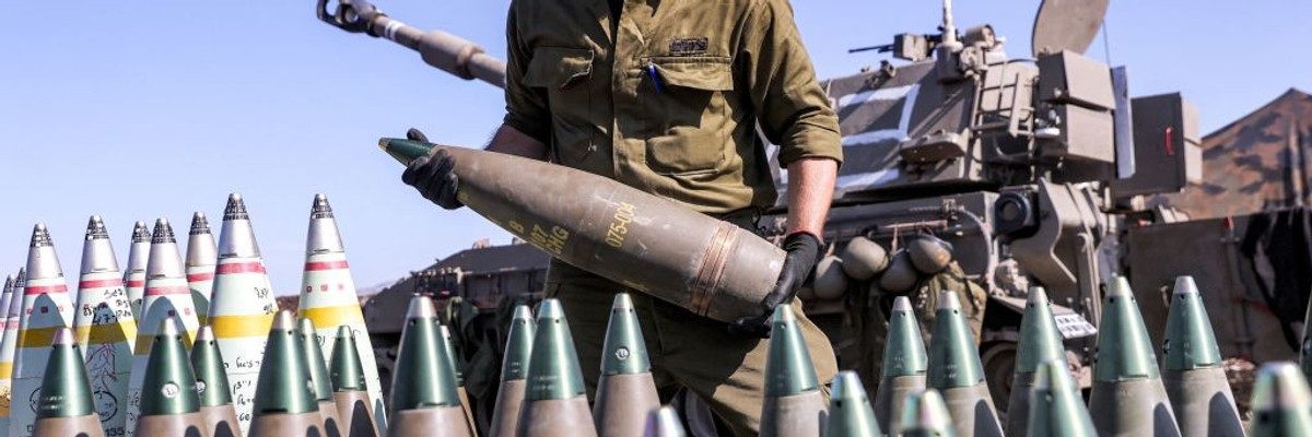 An Israeli soldier handles a 155mm artillery round