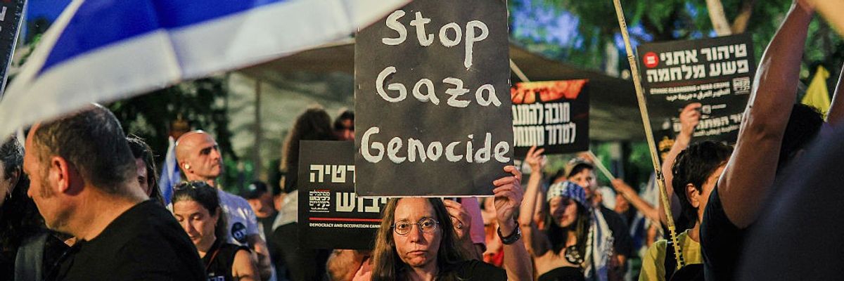 An Israeli woman holds a sign reading "Stop Gaza Genocide" at a Tel Aviv protest