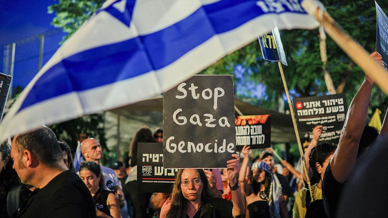 An Israeli woman holds a sign reading "Stop Gaza Genocide" at a Tel Aviv protest