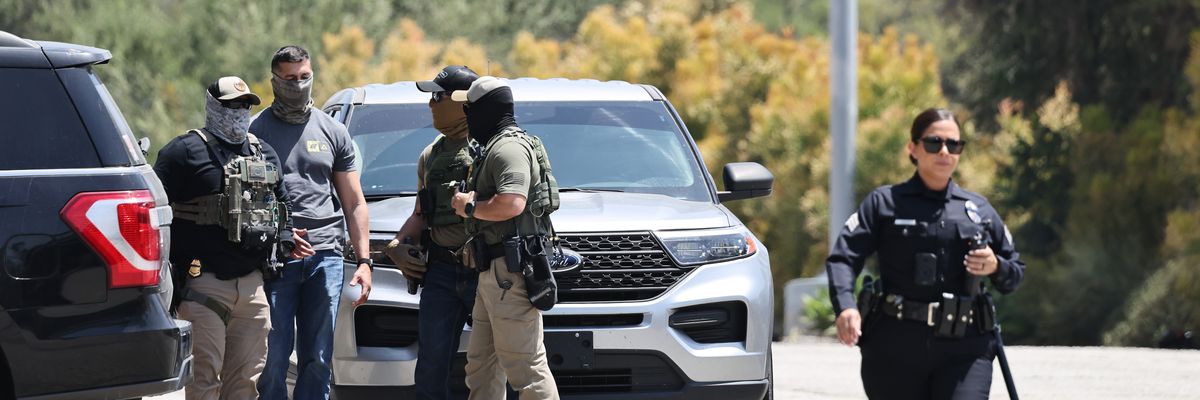 An LAPD officer walks near masked federal agents