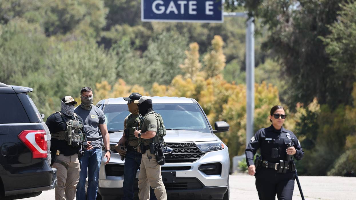 An LAPD officer walks near masked federal agents