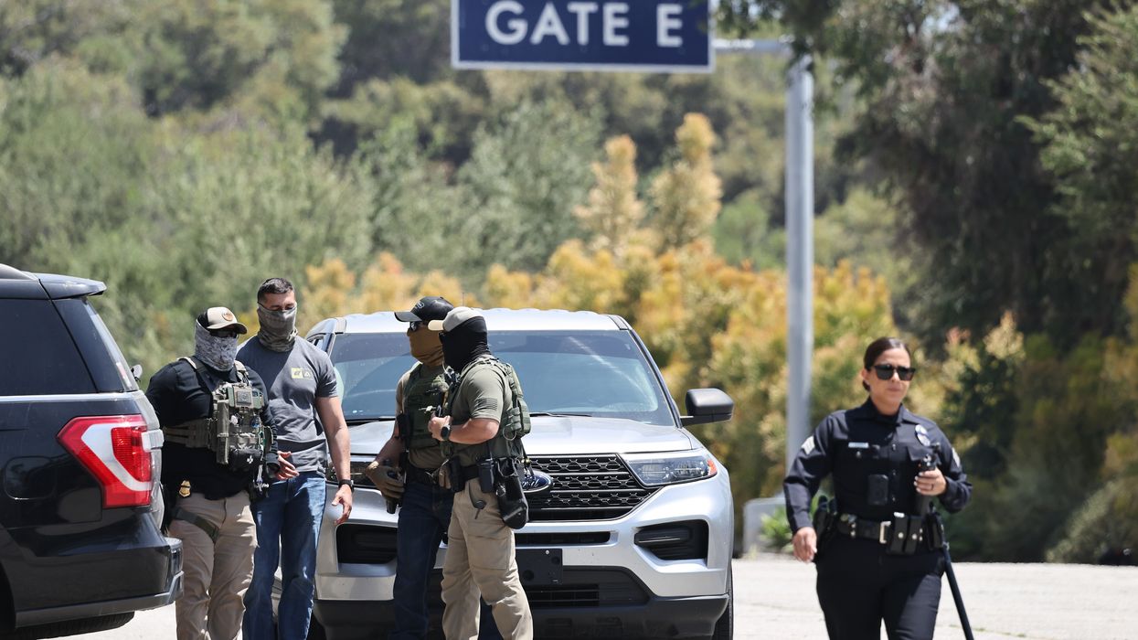 An LAPD officer walks near masked federal agents