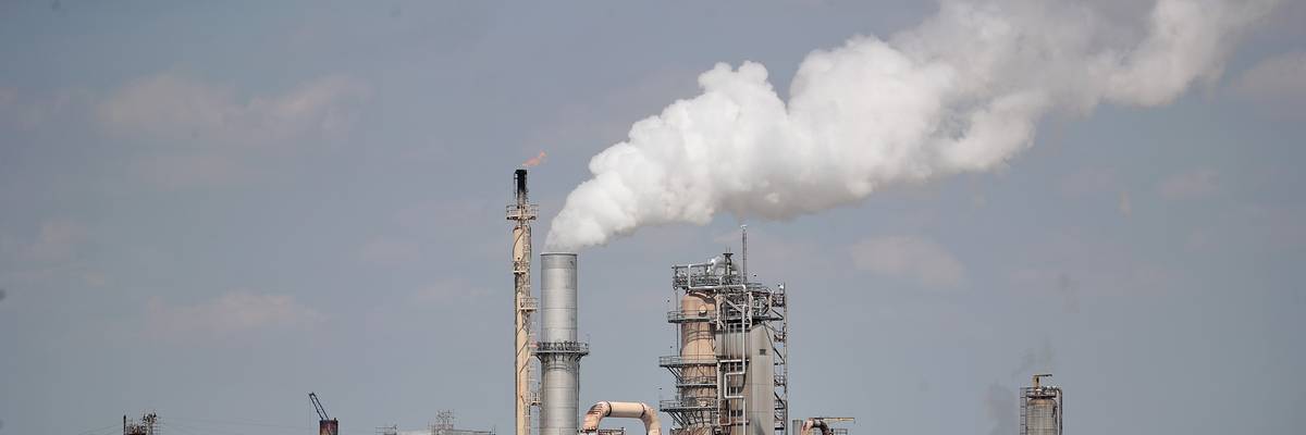 An oil refinery releases smoke.