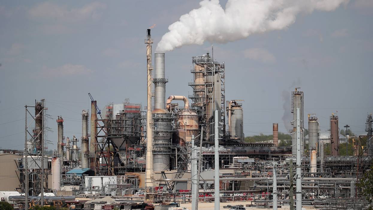 An oil refinery releases smoke.