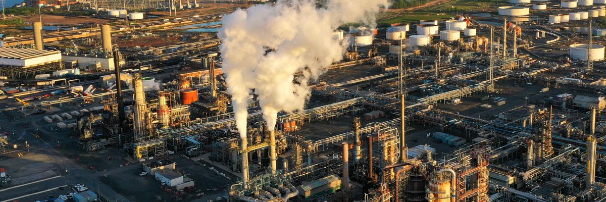 an oil refinery spews smoke