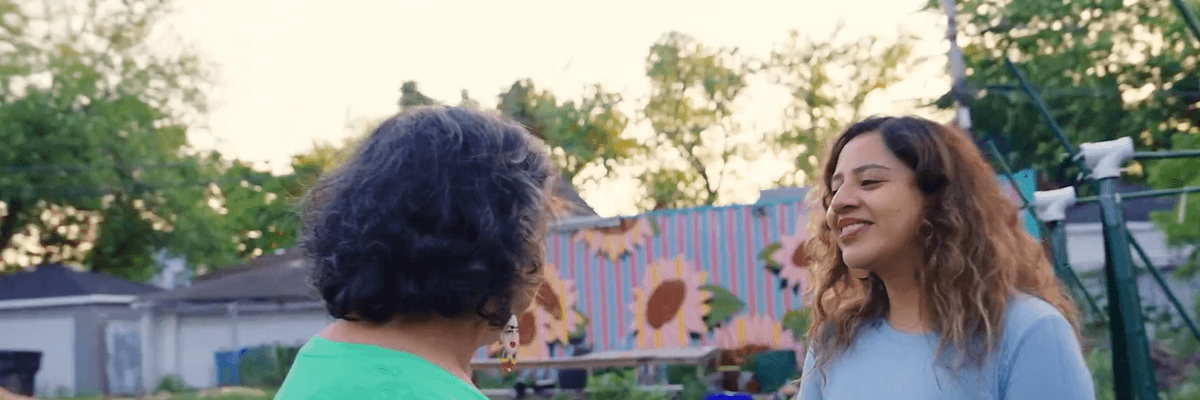 An organizer speaks to a woman in a community garden.