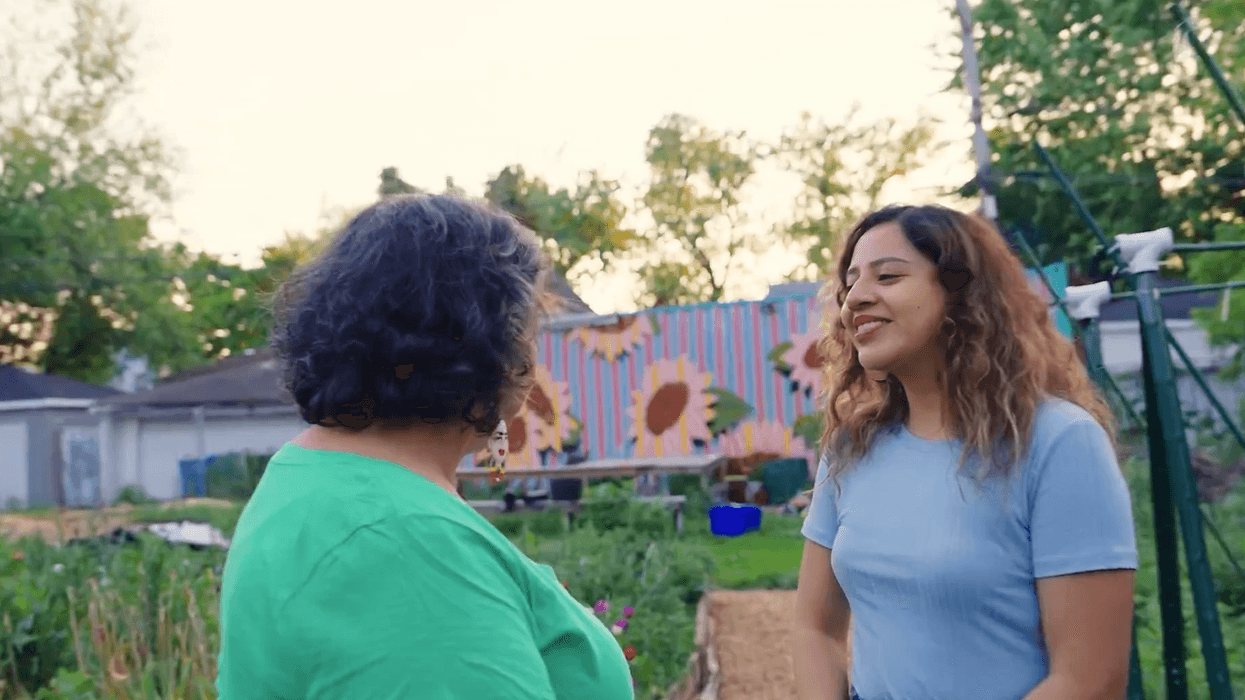 An organizer speaks to a woman in a community garden.