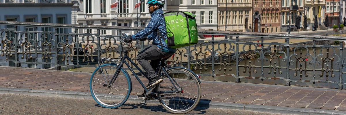 An Uber Eats delivery courier on bicycle on his way to deliver fast food in Ghent-Belgium on May 15, 2020.
