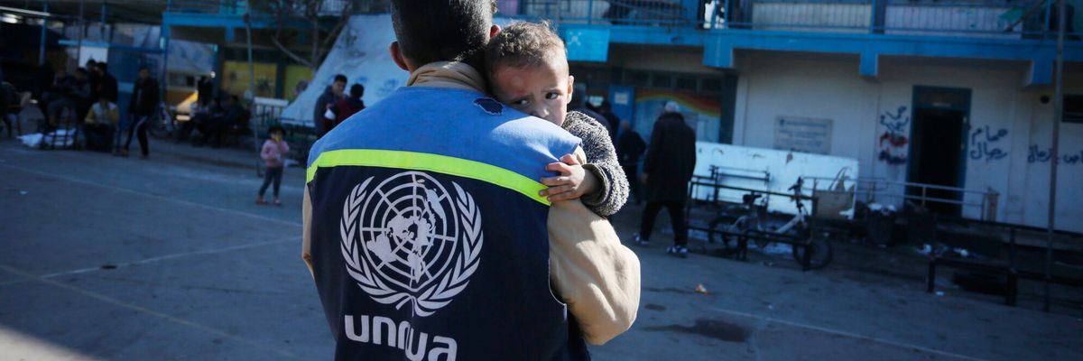 An UNRWA staffer holds a traumatized Palestinian baby in Gaza.