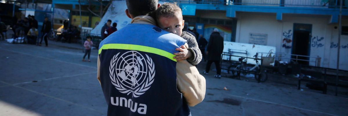 An UNRWA staffer holds a traumatized Palestinian baby in Gaza.