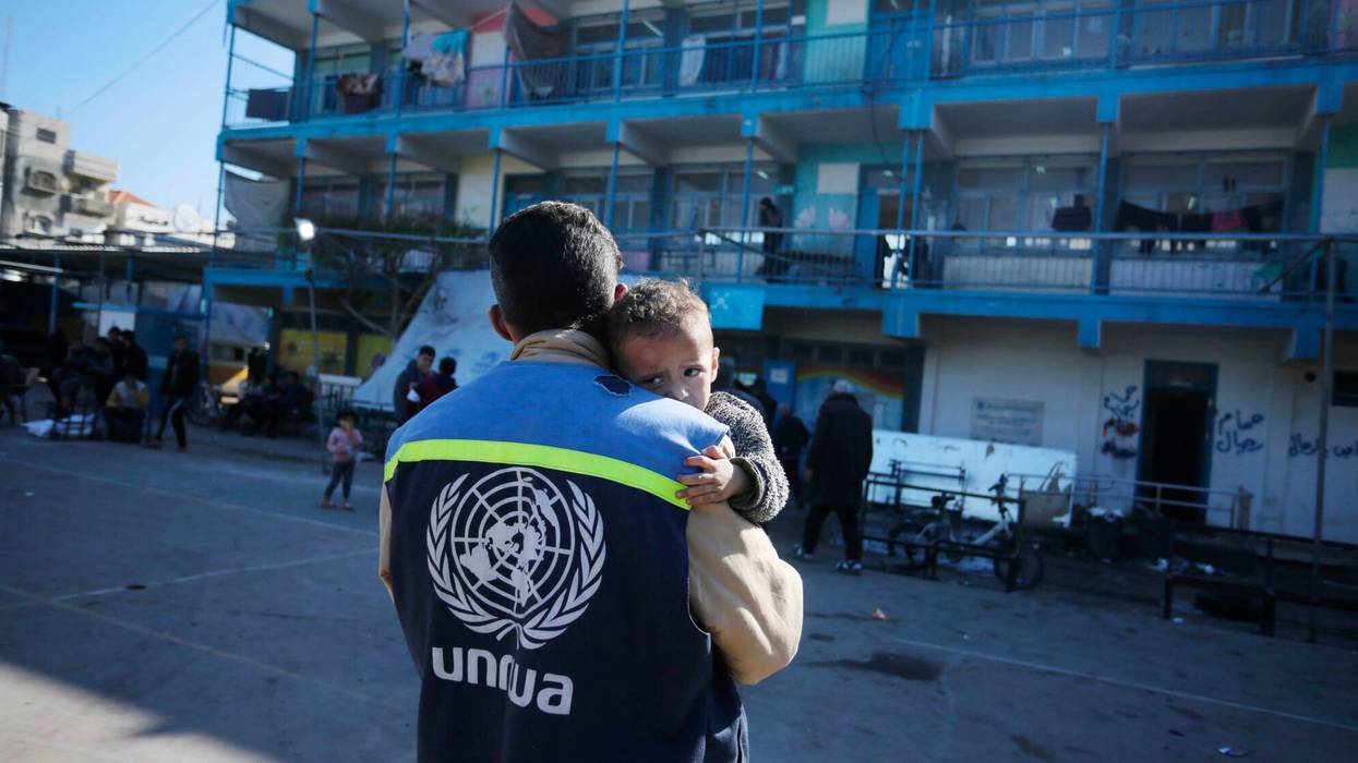 An UNRWA staffer holds a traumatized Palestinian baby in Gaza.