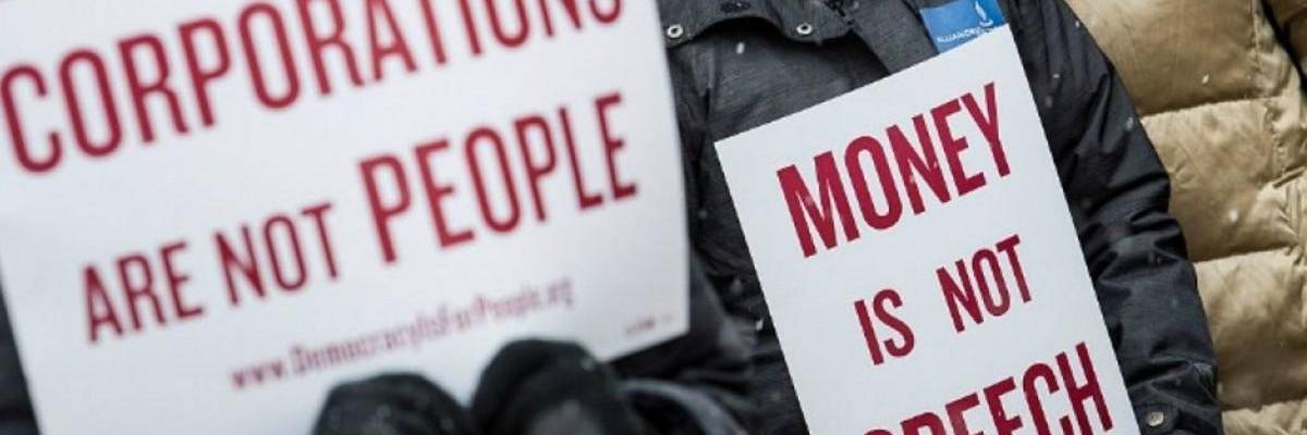 anti-Citizens United protesters hold signs reading "corporations are not people" and "money is not speech."