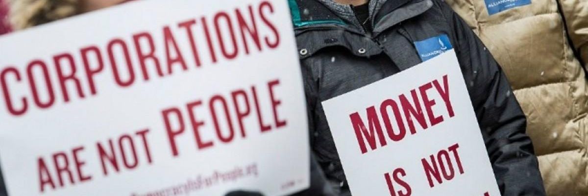 anti-Citizens United protesters hold signs reading "corporations are not people" and "money is not speech."