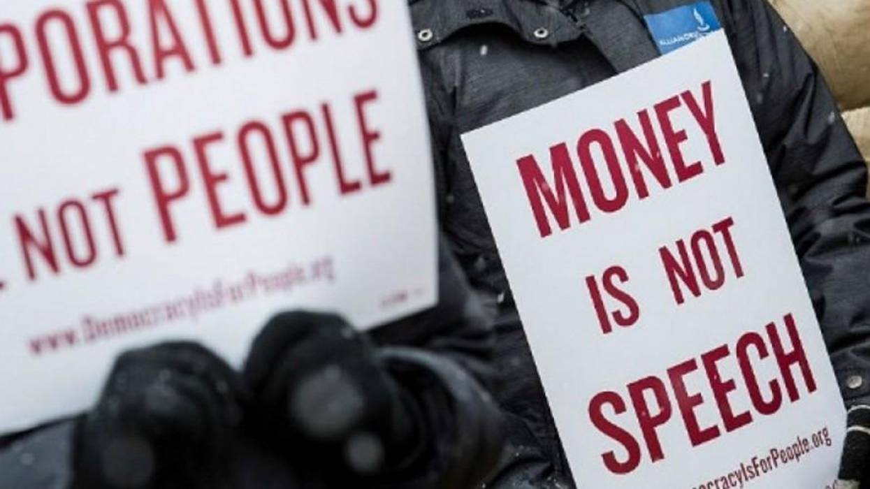 anti-Citizens United protesters hold signs reading "corporations are not people" and "money is not speech."