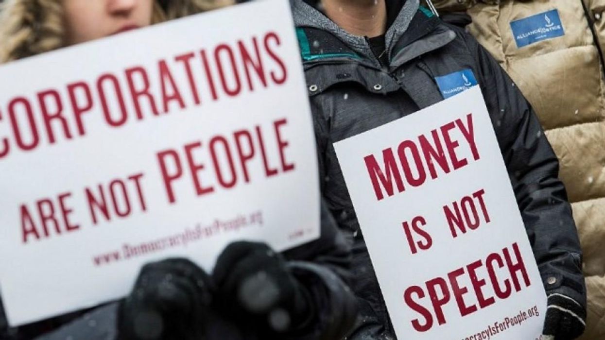 anti-Citizens United protesters hold signs reading "corporations are not people" and "money is not speech."