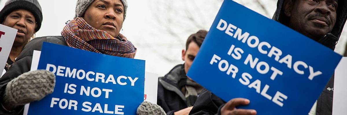 Anti-Citizens United protesters hold signs reading, "Democracy Is Not for Sale" during a winter protest
