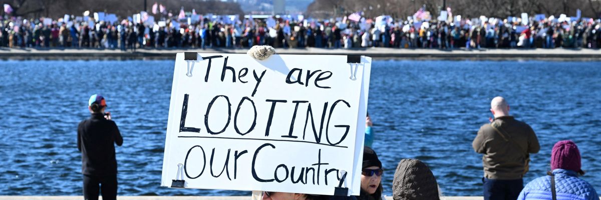 Anti-Trump protest with sign saying, "They are looting our country."