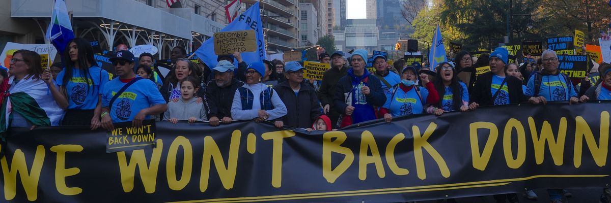 Anti-Trump protesters carry sign reading, "We won't back down."