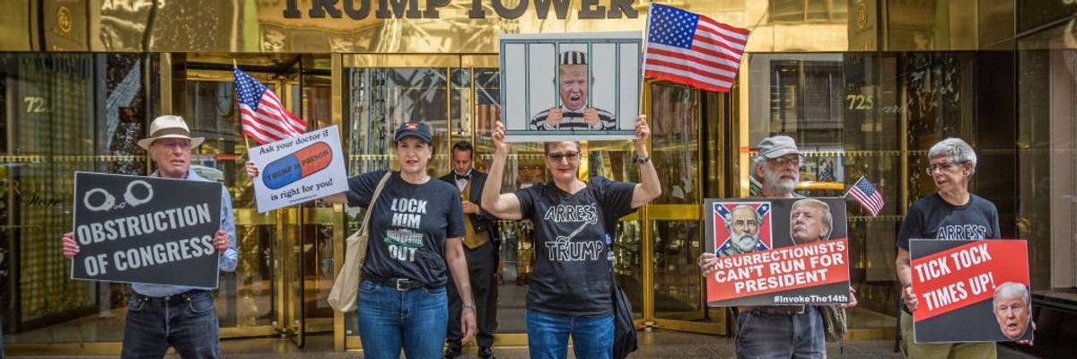 Anti-Trump protesters stand with signs in front of Trump Tower.