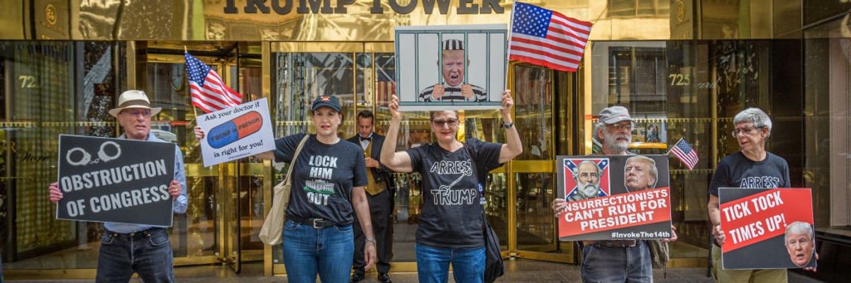 Anti-Trump protesters stand with signs in front of Trump Tower.