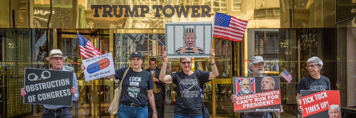 Anti-Trump protesters stand with signs in front of Trump Tower.