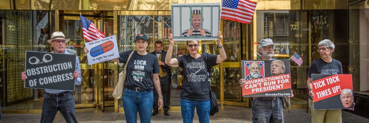 Anti-Trump protesters stand with signs in front of Trump Tower.