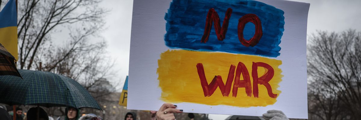 Anti-war demonstrators carry a sign saying, "No war" in the colors of the Ukrainian flag.