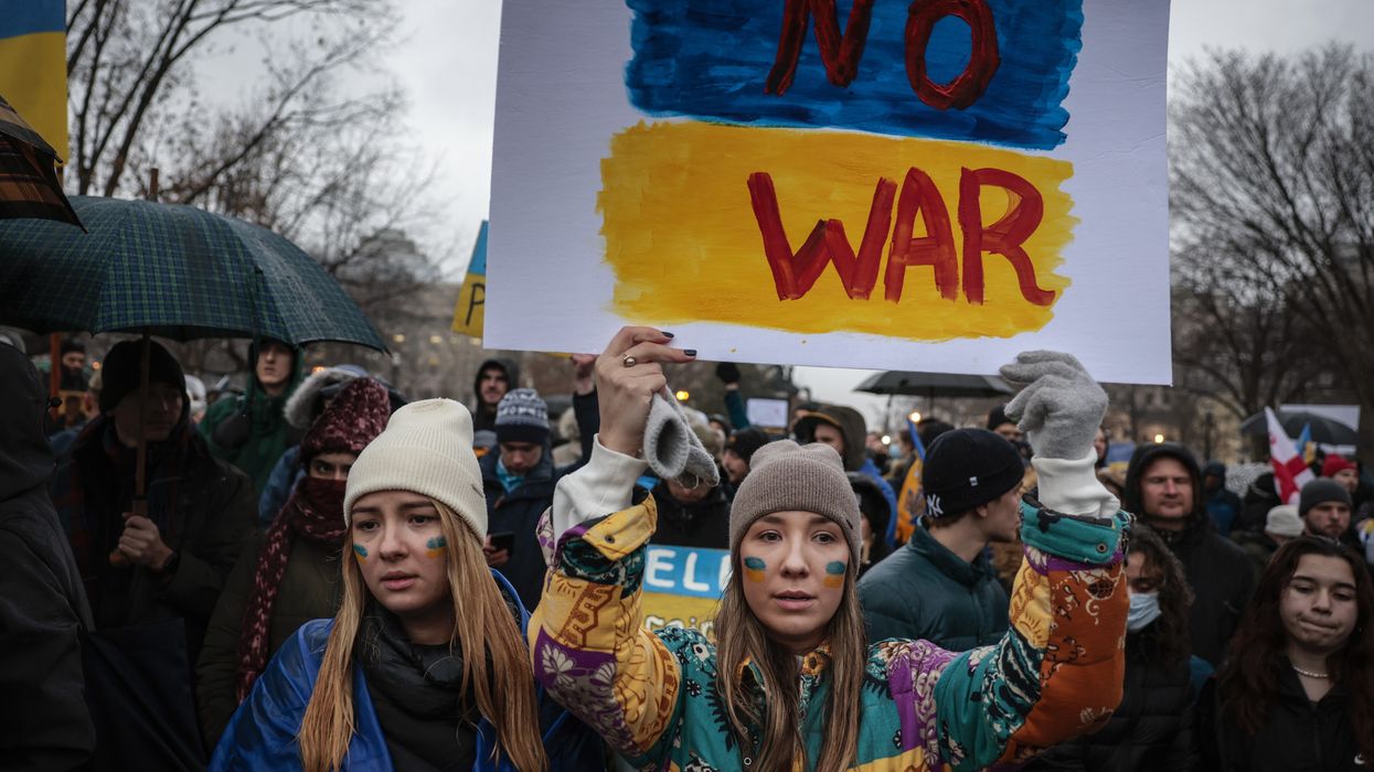 Anti-war demonstrators carry a sign saying, "No war" in the colors of the Ukrainian flag.