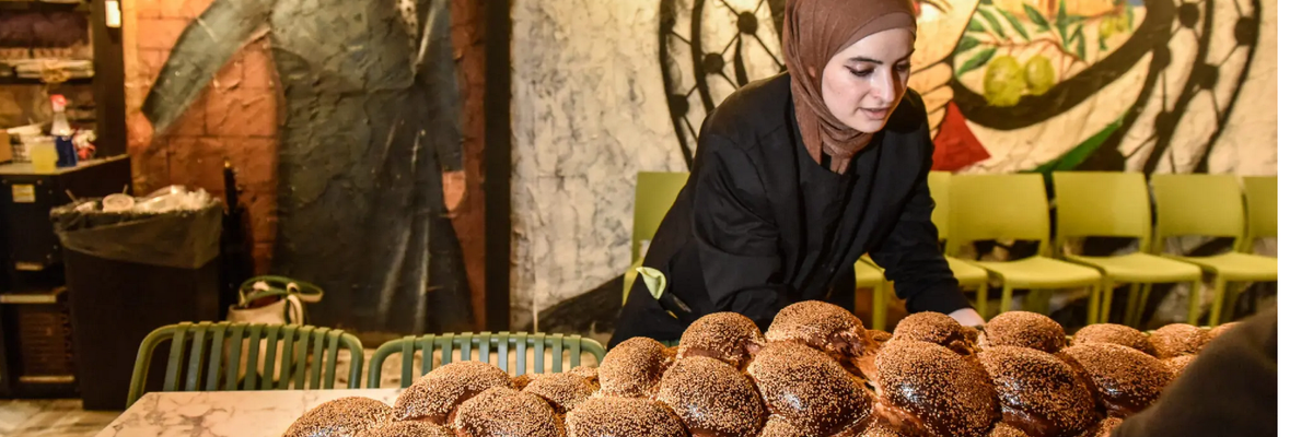 Arabic women set out a giant challah for an inter-faith Shabbat dinne