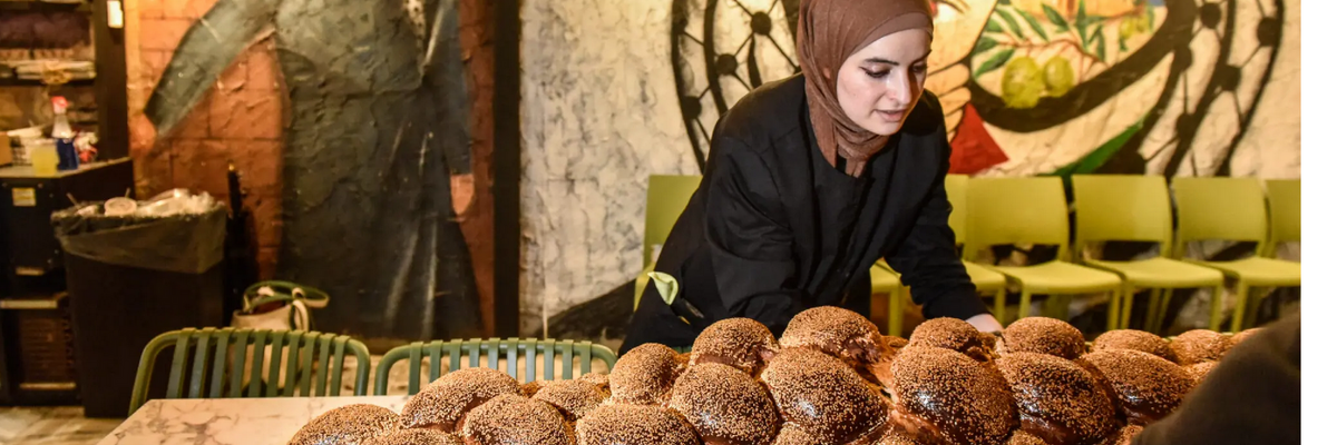 Arabic women set out a giant challah for an inter-faith Shabbat dinne 