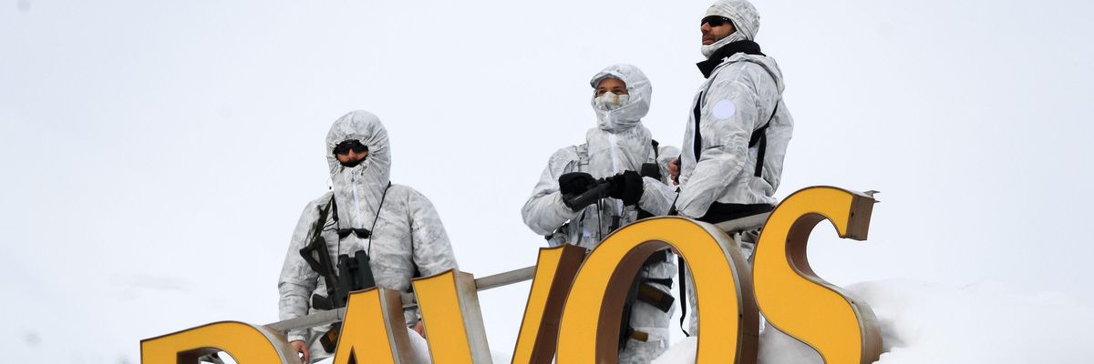 Armed security personnel stand guard on the rooftop of a hotel, next to letters reading "Davos"